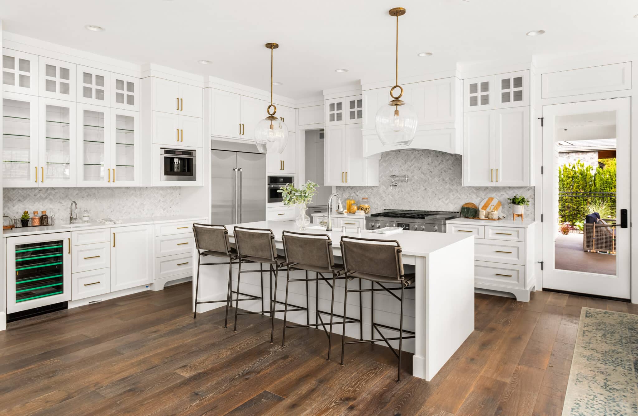 Beautiful white kitchen in new luxury home, with waterfall island, stainless steel appliances, and hardwood floors